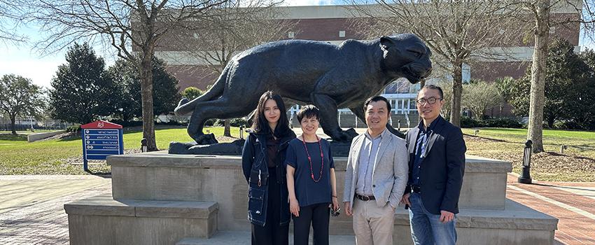 International guests on USA campus in front of Jaguar statue.